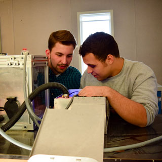 Two students working with a machine