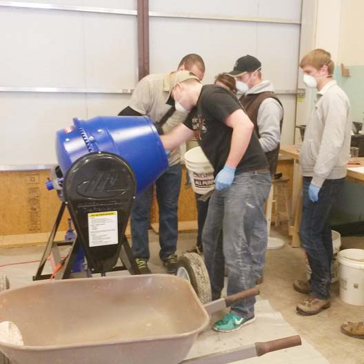 Engineering students mix concrete for a canoe project