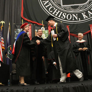 Graduate shaking hands with faculty at Graduation