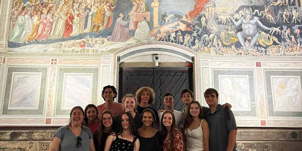 A group of students in front of a mural in Italy.