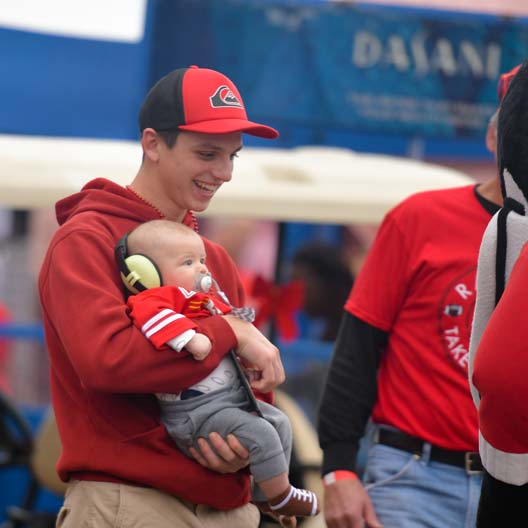 A father holds his baby at the Benedictine College tailgate for the 2018 NAIA Football Championship