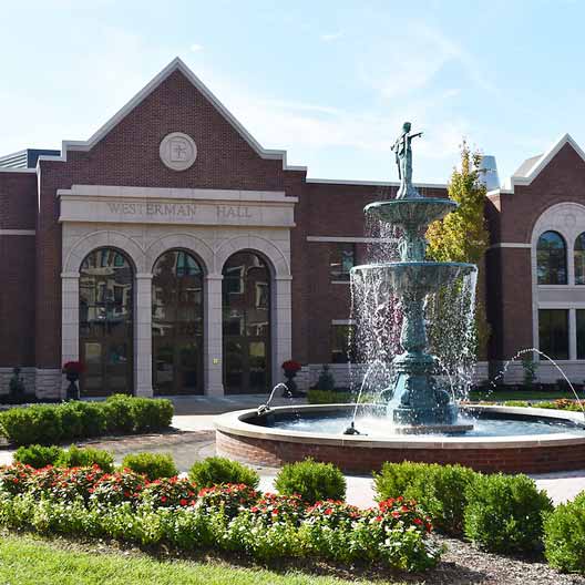The facade of Westerman Hall, viewed from the quad with Our Lady of Grace Fountain in the foreground
