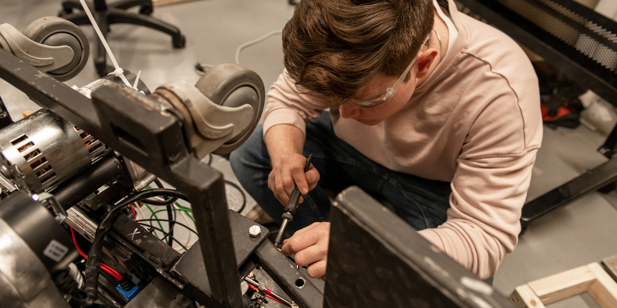 Mechanical Engineering student fixing a machine with a screwdriver