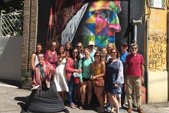 Students on Journey with Dante posing for a photo at a mural in Italy