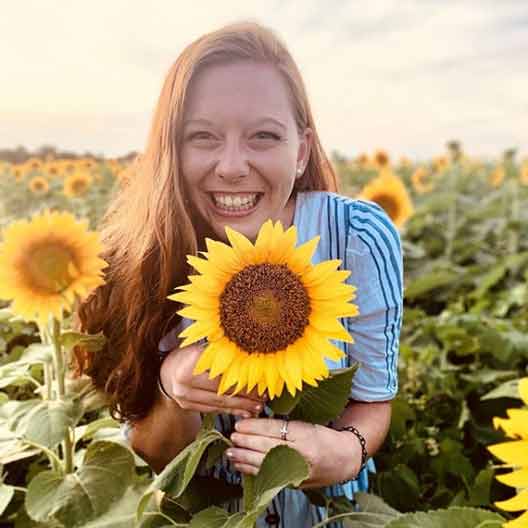 A student in a field of sunflowers