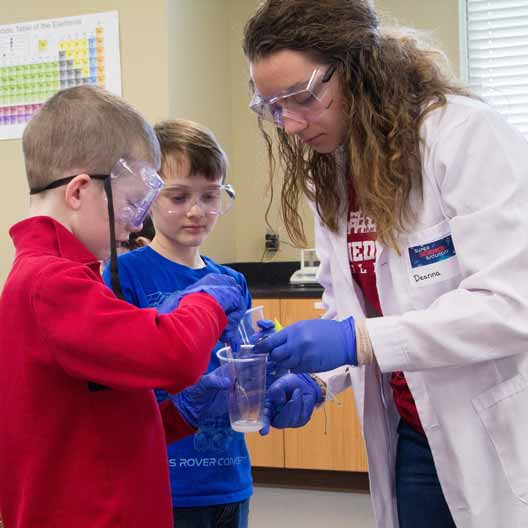 A students works with two children in a lab