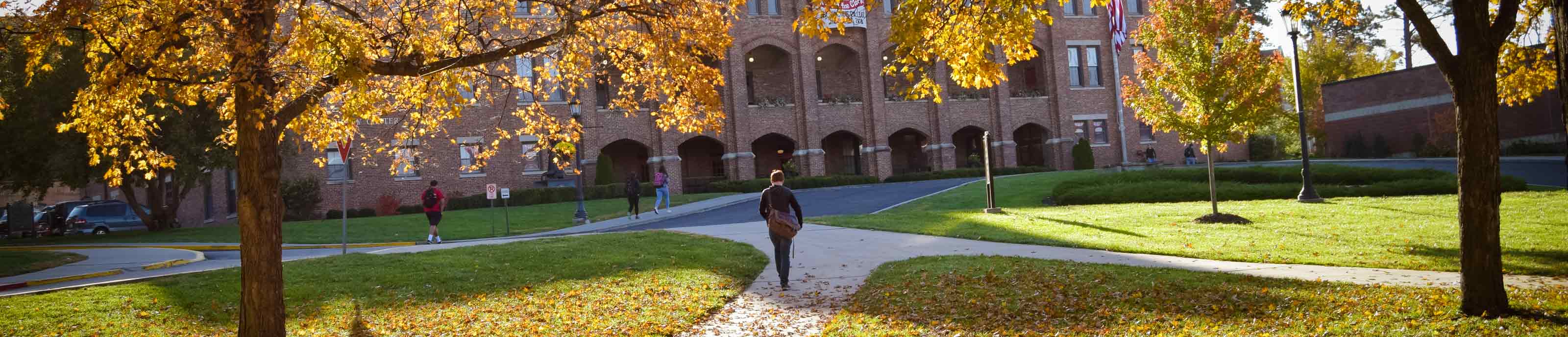 A student walks on an autumn Benedictine College campus