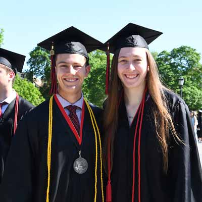 Graduates in cap and gown posing for a photo