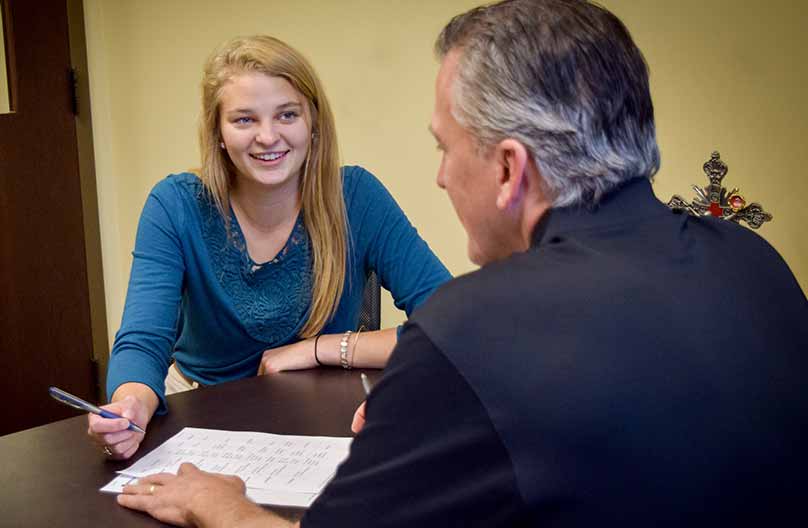 A professor speaks to a student in an office