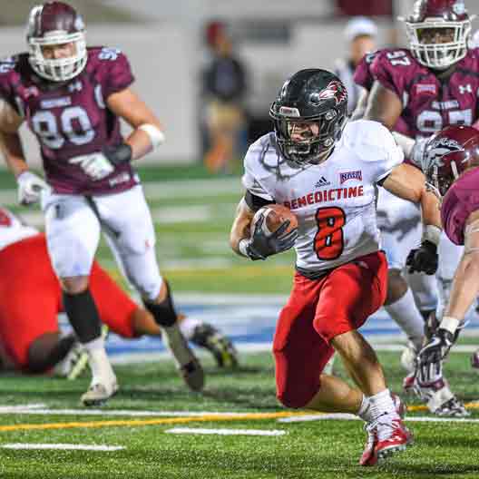 A student football player in possession of the ball during a game