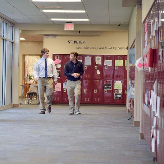 Two men walking along a school hallway