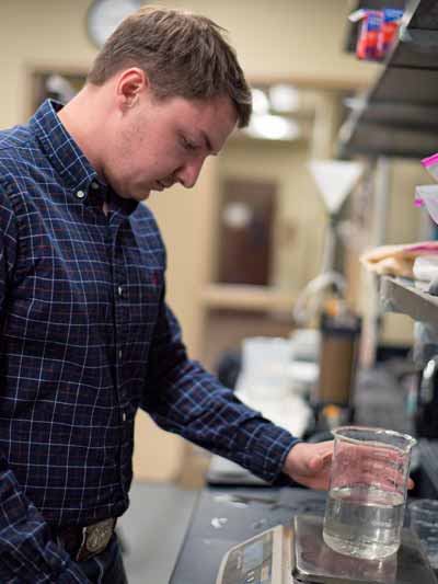 A student works with a glass beaker in Engineering class