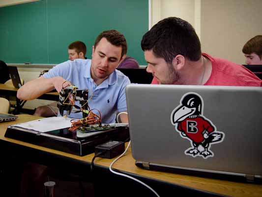 Students working with a robotic arm in engineering class