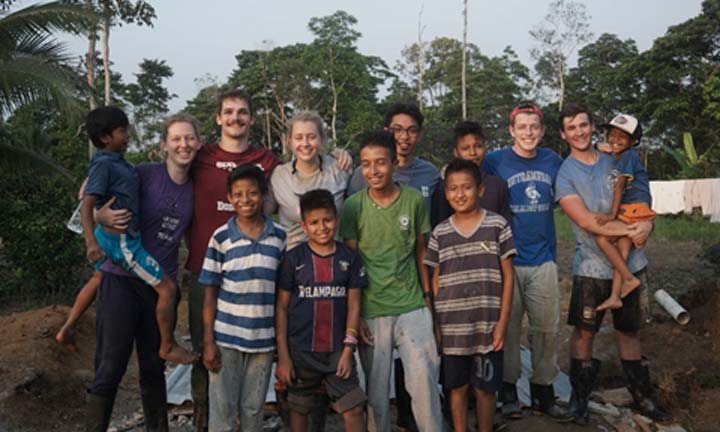 Students pose with children while on a mission trip