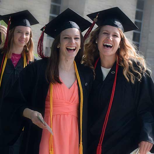 Two graduates laughing in their cap and gowns