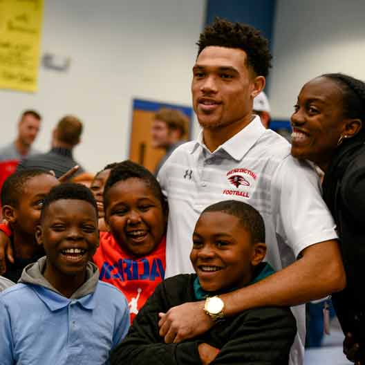 A student poses for a photo with multiple children