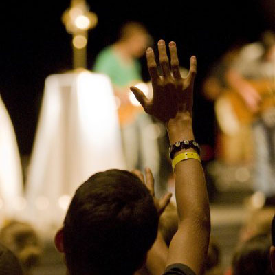 A young student raises his hand in prayer during adoration