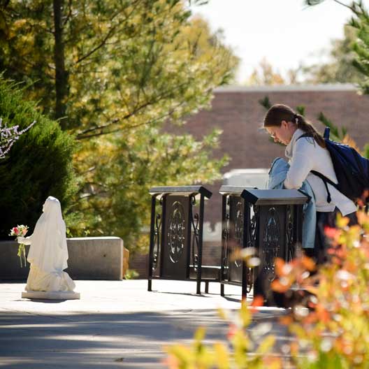 Student praying at Mary's Grotto