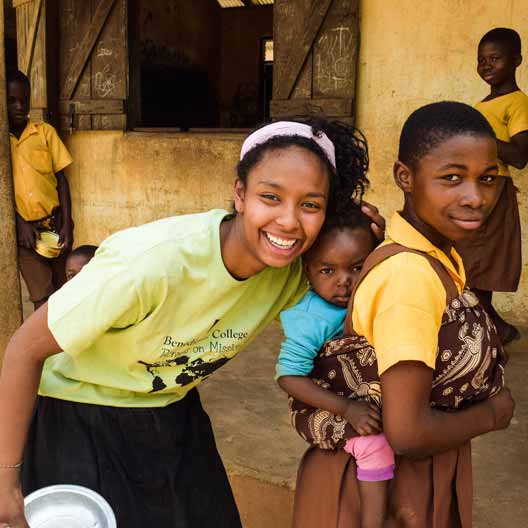 A Benedictine College student poses hugging a child in Ghana