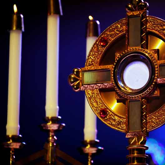 A monstrance holding the Blessed Sacrament, and candles