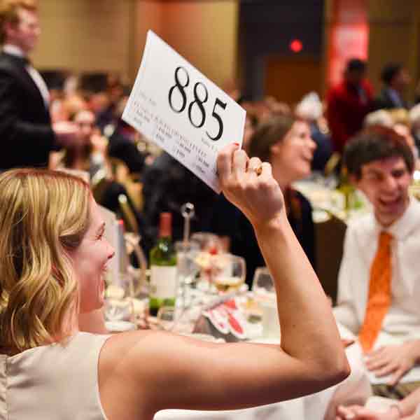 A Scholarship Ball attendee holds up her bid card during Fund-A-Raven