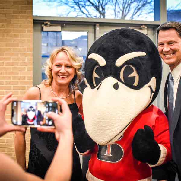 Scholarship Ball attendees pose for a photo with Rocky the Raven