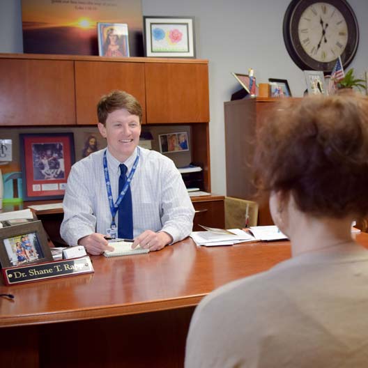 A school principal meets with a person in his office