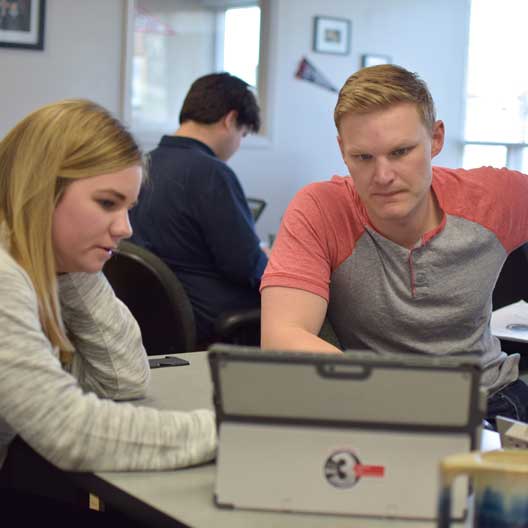 Graduate students work together at a computer during class