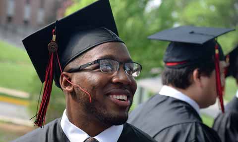 A graduate stands outside in cap and gown