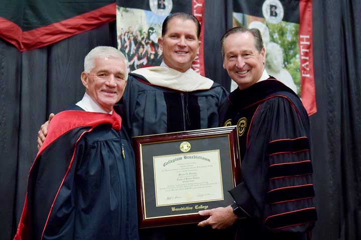2019 Benedictine College Commencement Speaker Mike Sweeney receives his honorary degree from President Stephen Minnis, with Chairman of the Board Jack Newman alongside.