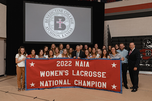 Champions - Lou Holtz poses with the 2022 National Champion Women's Lacrosse team.