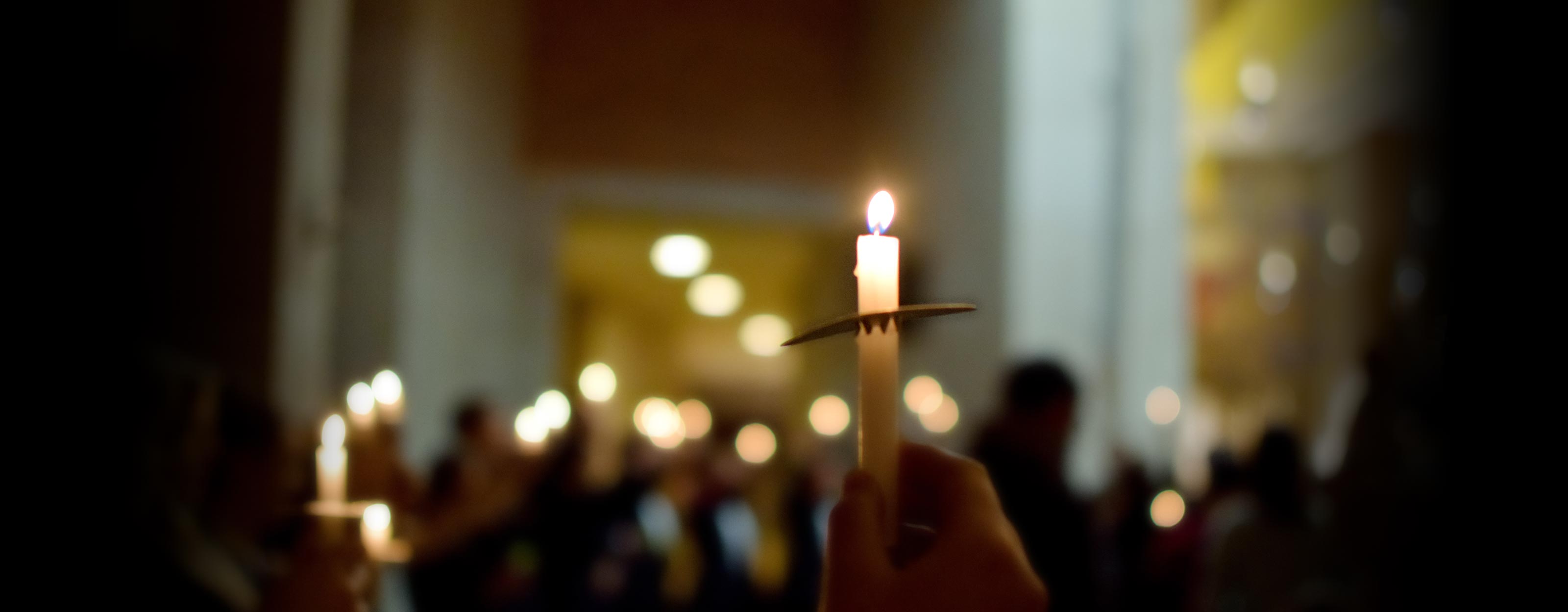 A hand holds a candle during a prayer service
