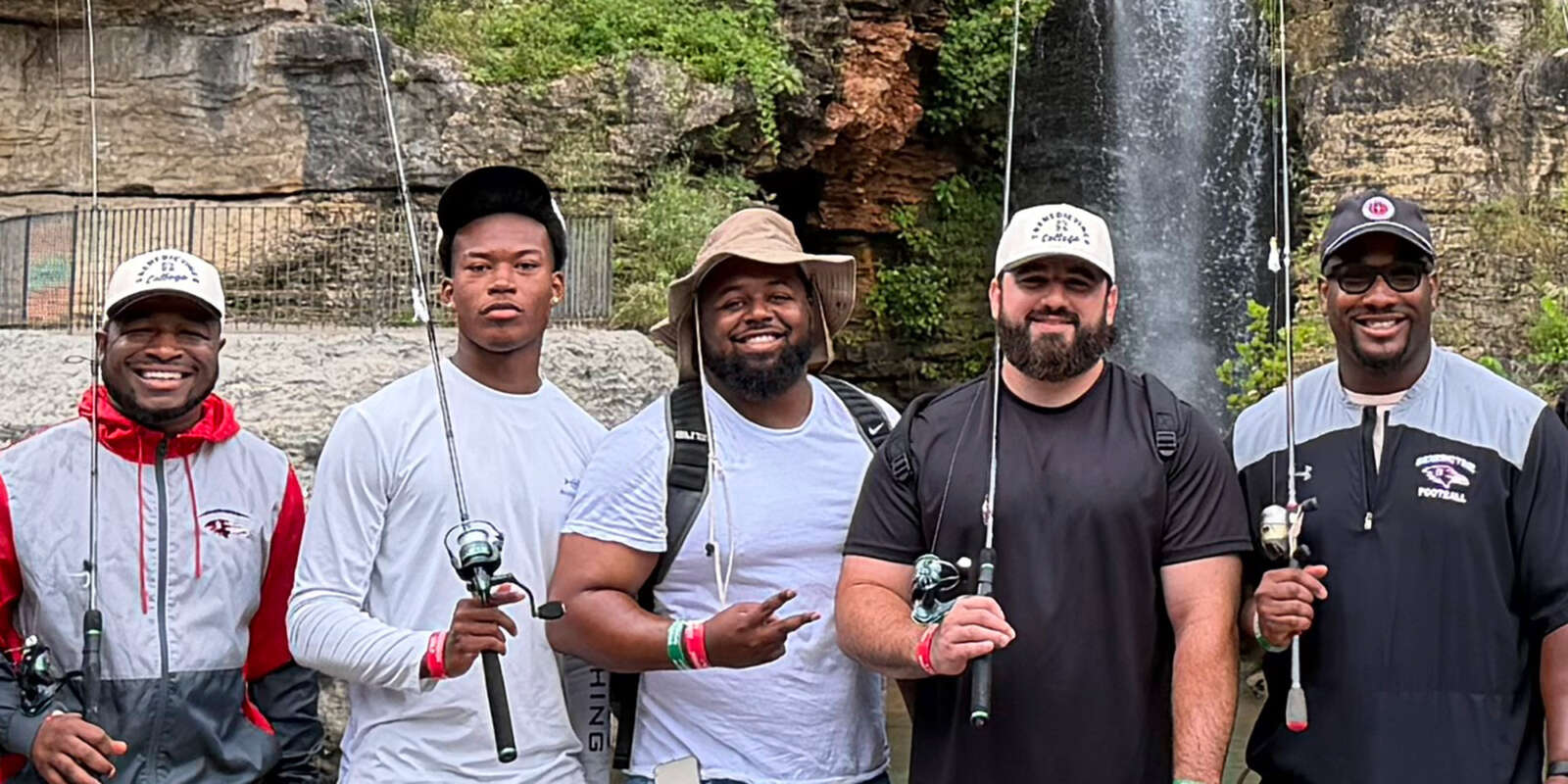 Students pose for a photo holding fishing rods