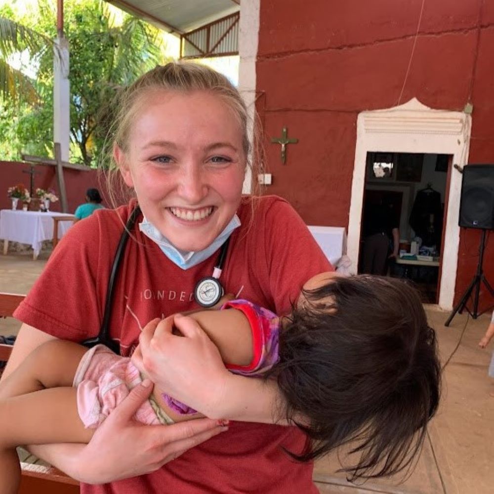A student holds a child in her arms while on a mission trip
