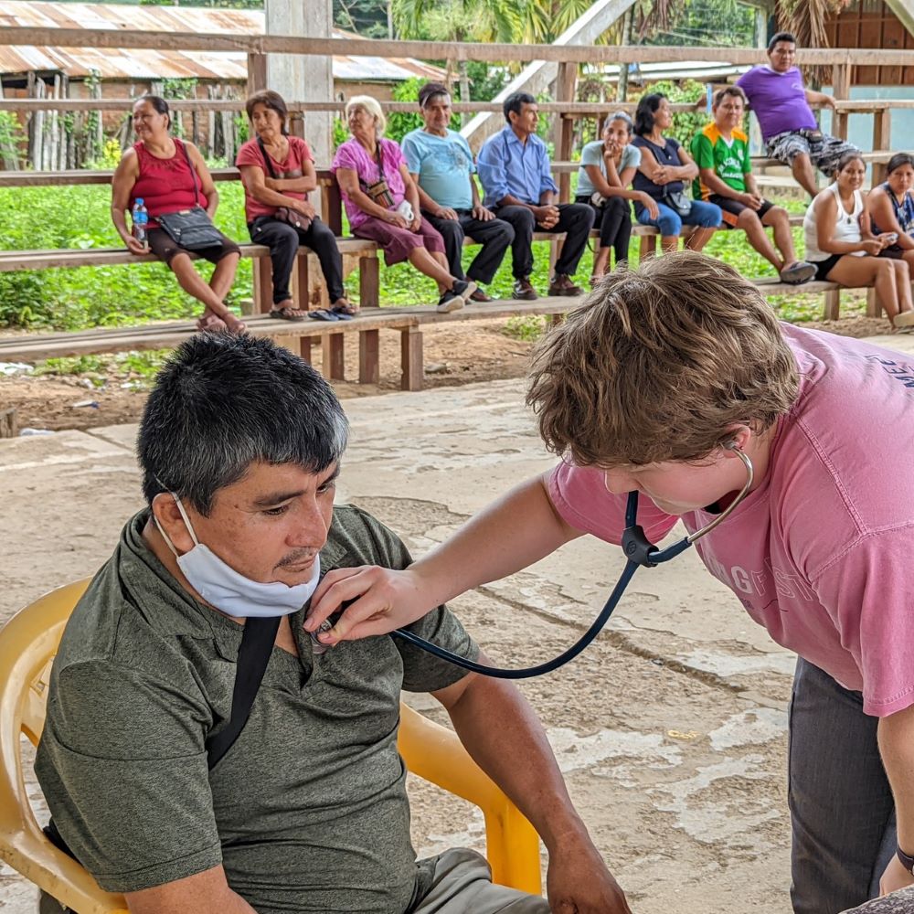 A health worker uses a stethoscope to listen to a man breathing