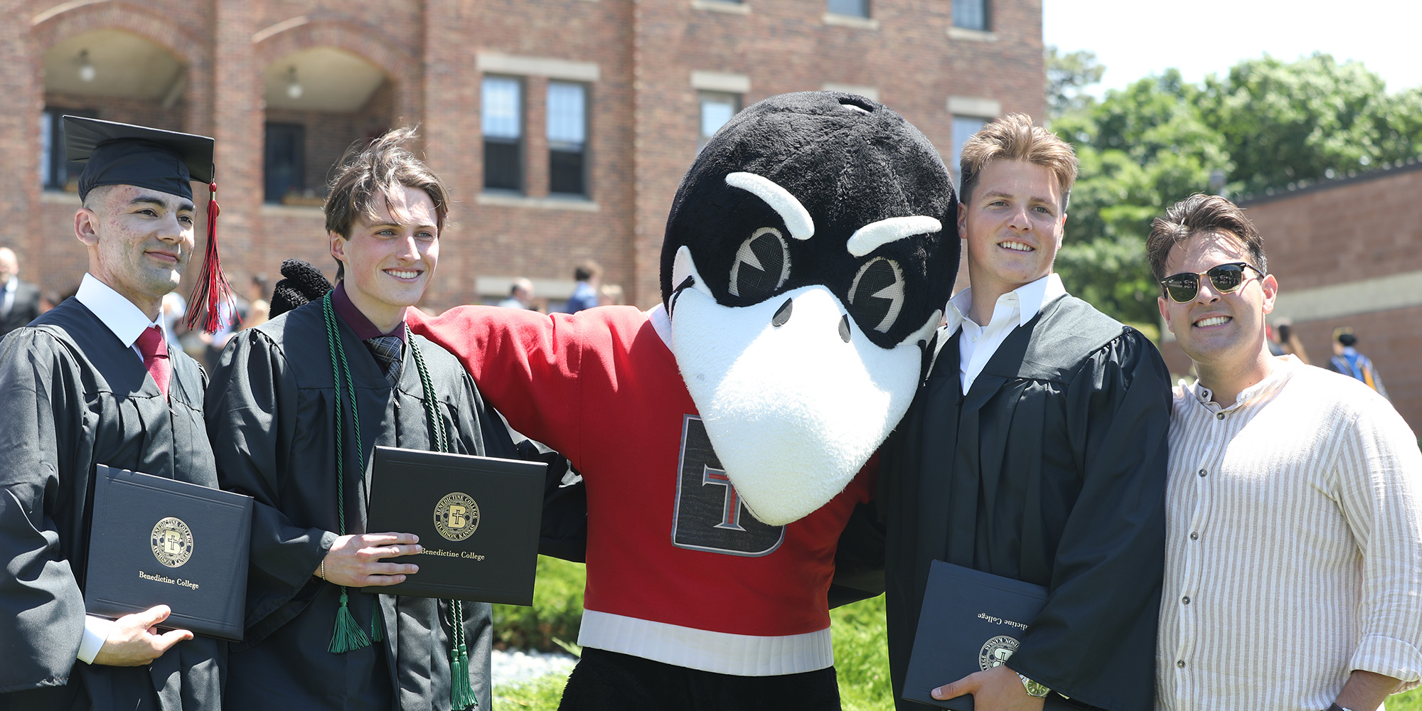 Graduates pose for a photo with Rocky the Raven after Commencement