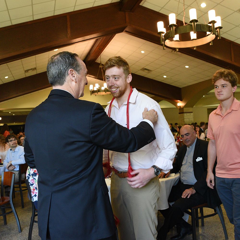 A graduate receives his honor cord at the Champagne Brunch