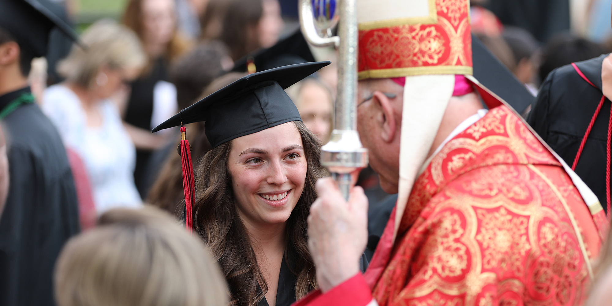 A graduate speaks to Archbishop Emeritus Joseph Naumann after the Baccalaureate Mass