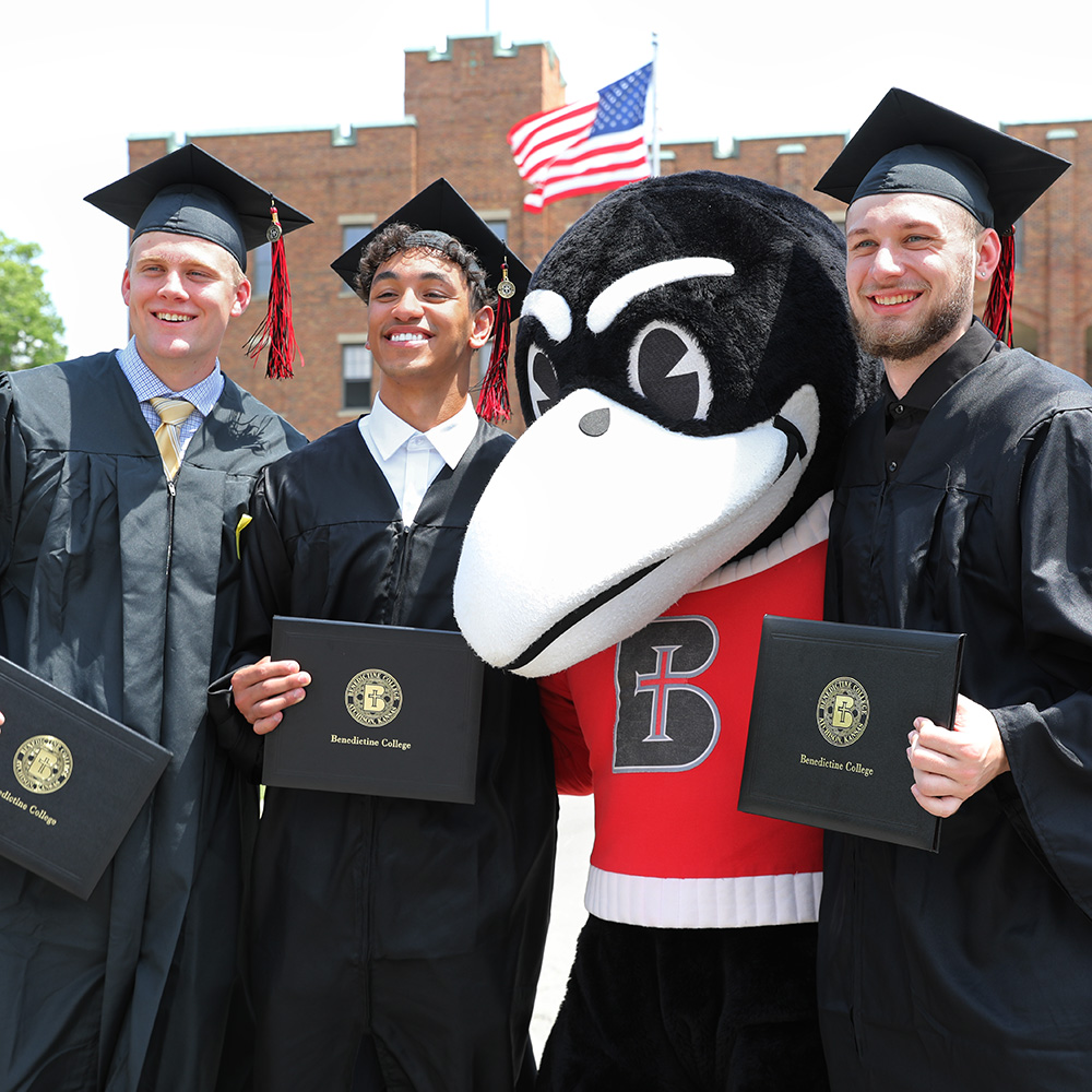 Graduates pose for a photo with Rocky the Raven after Commencement
