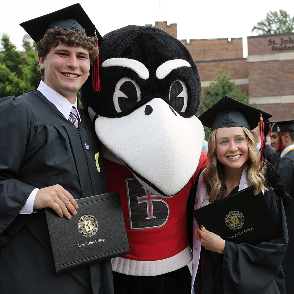 Graduates pose for a photo with Rocky the Raven after Commencement