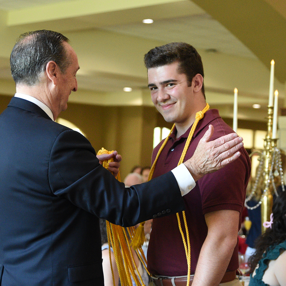 A graduate receives his honor cord at the Champagne Brunch