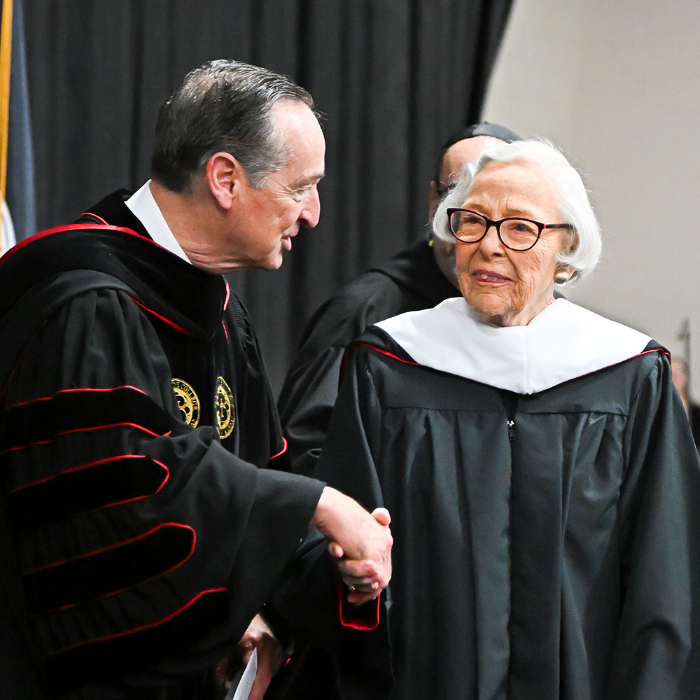 President Stephen Minnis shakes hands with 2026 Honorary Doctorate of Humane Letters Mary Ann Carney Skolaut