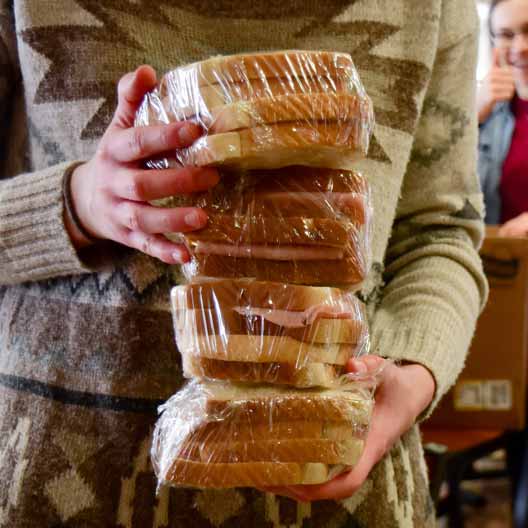 A person holds a stack of sandwiches